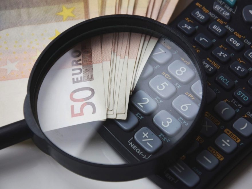 Banknoty euro, kalkulator i lupa symbolizujące analizę finansową przy obliczaniu alimentów.