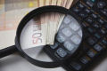 Banknoty euro, kalkulator i lupa symbolizujące analizę finansową przy obliczaniu alimentów.