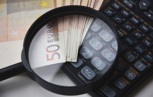 Banknoty euro, kalkulator i lupa symbolizujące analizę finansową przy obliczaniu alimentów.