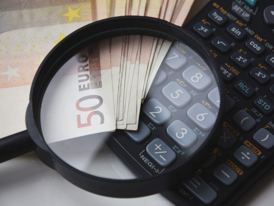 Banknoty euro, kalkulator i lupa symbolizujące analizę finansową przy obliczaniu alimentów.